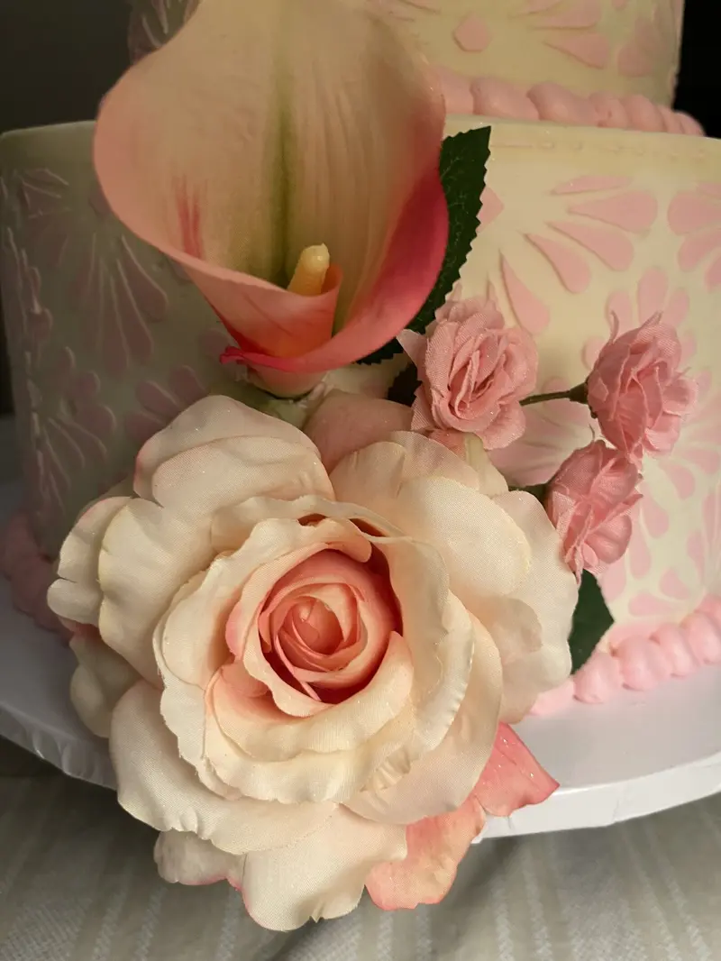 Close-up of roses and calla lilies on a stenciled tiered cake