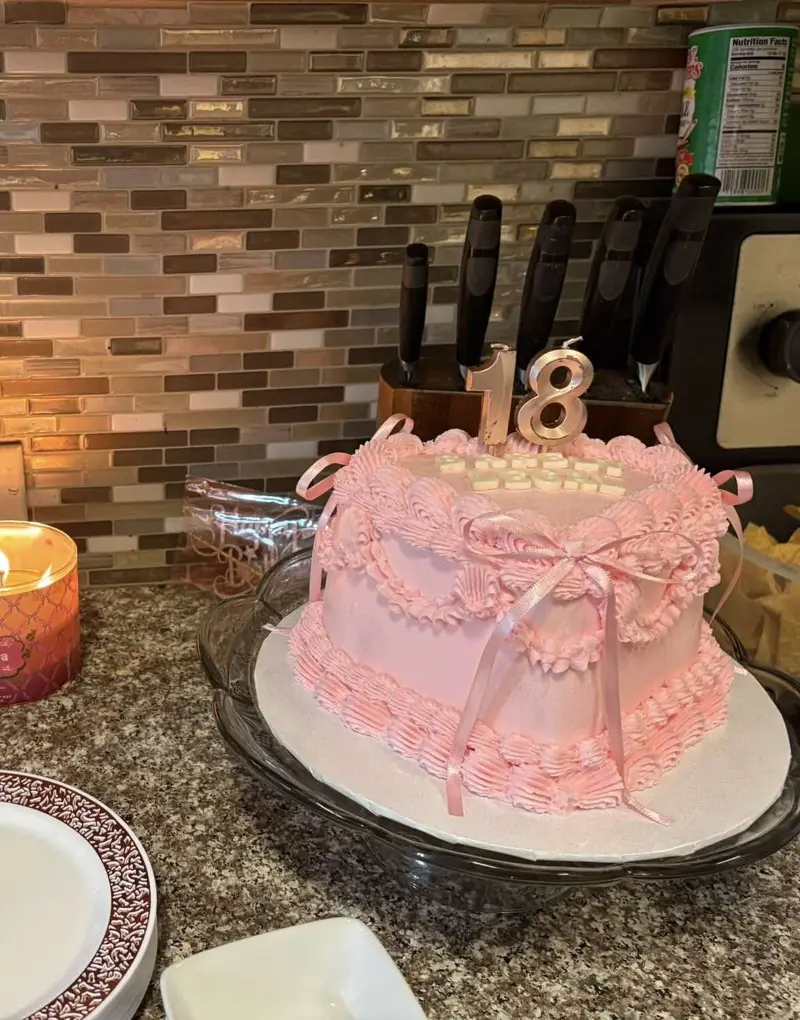 Pink heart-shaped vintage cake with ribbon bows and a silver 18 topper