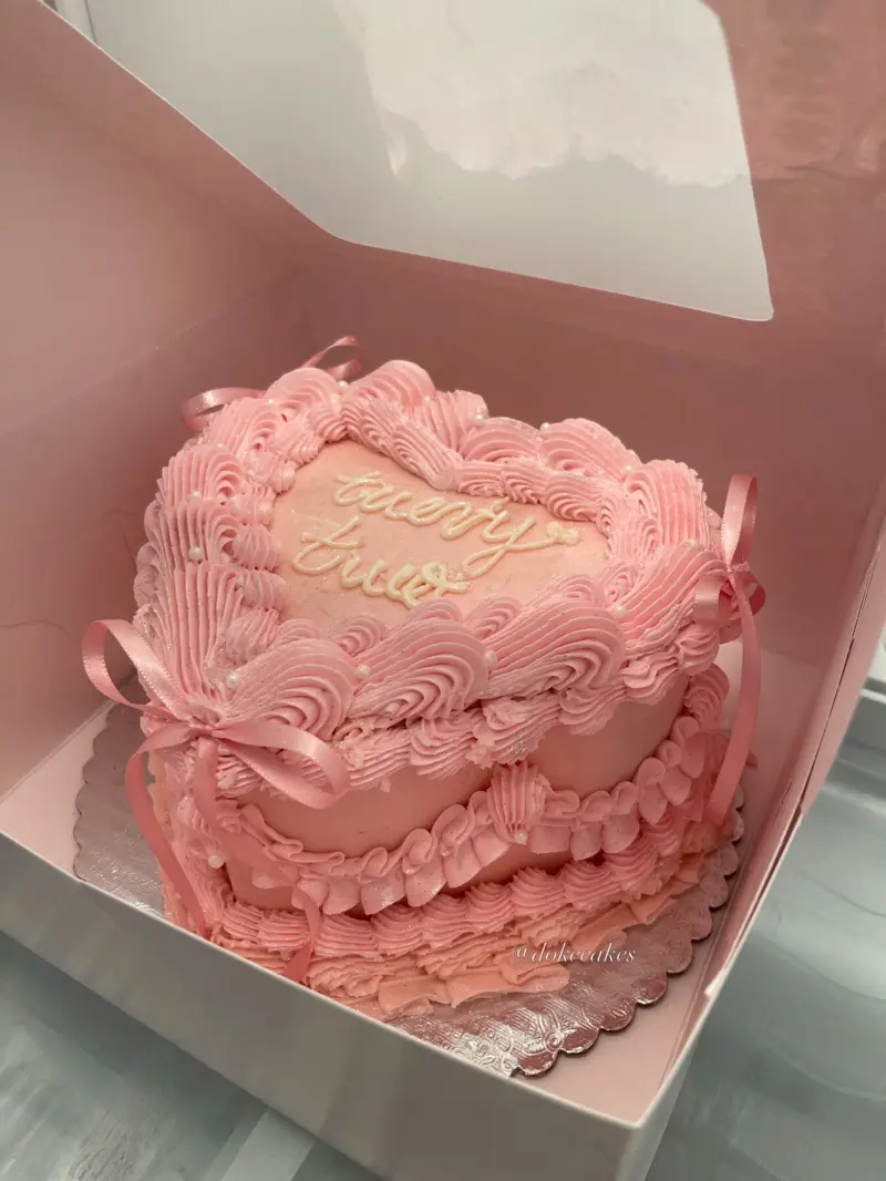 Pink heart-shaped vintage cake with ruffled piping and satin ribbons